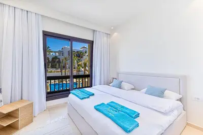 a white bedroom with a large bed and a window at Stylishly furnished and quietly located apartment in Hurghada