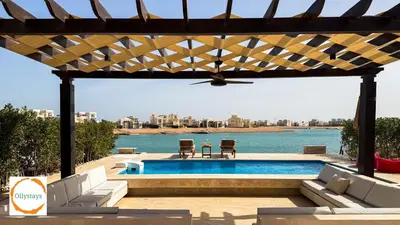 a swimming pool with a pergola next to the water at Ancient Sands 4BR Villa Heated pool in El Gouna
