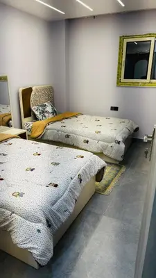 a bedroom with two beds and a chair and a mirror at Magwish in Hurghada