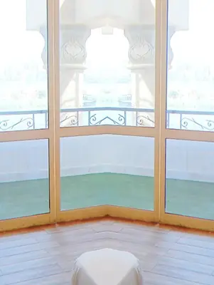 a room with two large windows and a white stool at VIP hotel & café in Qilfāw