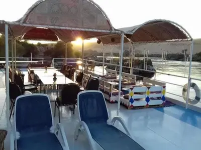 a boat with chairs and an umbrella on a boat at Shellaly Ca Nubian Heritage House in Jazīrat Salūjah