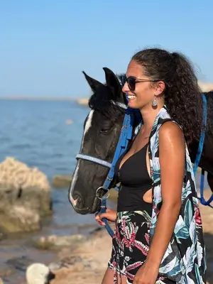 a woman standing next to a horse on the beach at Horse Riding Tour in Hurghada