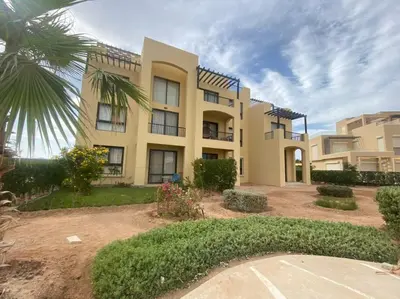 a large house with a palm tree in front of it at Lovely 1 bd apartment with amazing view in Tawila in Hurghada
