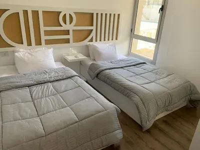 a bedroom with two beds and a window at 2bd direct on the main pool in Hurghada