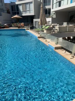a large blue swimming pool with chairs and an umbrella at 2bd direct on the main pool in Hurghada