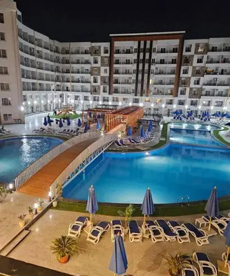 a large pool with chairs and umbrellas in a hotel at Tiba Golden Resort Hurghada in Hurghada