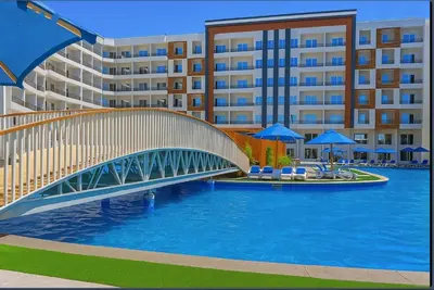 a bridge over a pool in front of a building at Tiba Golden Resort Hurghada in Hurghada