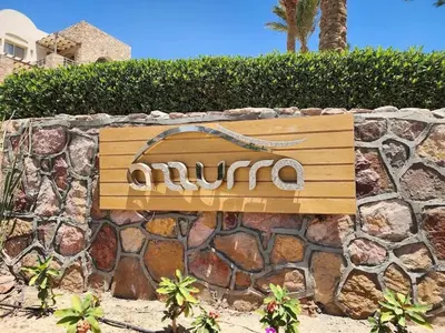 a wooden sign on a stone wall at Luxury 2BR Sea View Apt in Azzurra Sahl Hasheesh in Hurghada