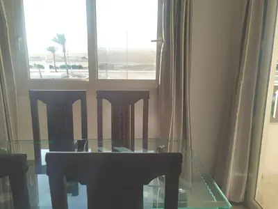 a glass table and chairs in a room with a window at Arietta Flat Amazing location in Avrio compound in Hurghada
