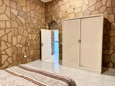 a bedroom with a bed and a stone wall at Nile Palace Villa in Luxor