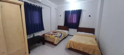 two beds in a room with blue curtains at Apartment with Balcony in Luxor
