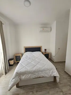 a white bedroom with a bed and two night stands at Aqua palms resort 2 bed flat C409 in Hurghada