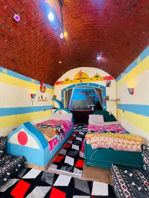 a bedroom with two beds in a room with a ceiling at Marwa House an Authentic Mud-Brick Home in Al Aqālitah