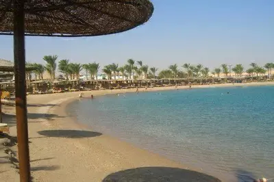 a beach with umbrellas and people in the water at Mirage Bay Resort Hurghada B-780 in Hurghada