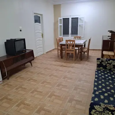 a living room with a table and chairs and a tv at Julia's Guest House in Shellal