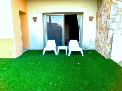 two white chairs sitting on a yard with green grass at Sahl hashesh Azzura apartment in Hurghada