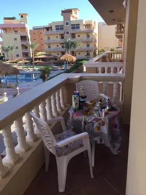 a table on a balcony with a view of a pool at Iris Holiday Apartament in Hurghada
