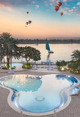 a group of hot air balloons flying over a swimming pool at Steigenberger Nile Palace Luxor - Convention Center in Luxor