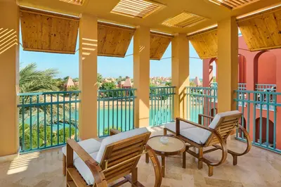 a balcony with chairs and a table and a view of a pool at Sheraton Miramar Resort El Gouna in Hurghada