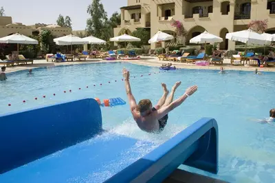 a man jumping off a ramp in a swimming pool at Three Corners Rihana Resort El Gouna in Hurghada