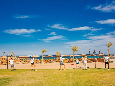 a group of people walking on the grass near the beach at Mercure Hurghada Hotel in Hurghada