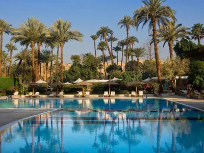 a large swimming pool with palm trees and umbrellas at Pavillon Winter Luxor in Luxor