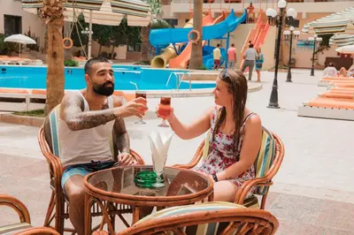 a man and a woman sitting at a table with drinks at Empire Hotel Aqua Park in Hurghada