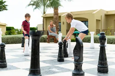 two boys playing chess on a giant chessboard at Three Corners Fayrouz Plaza Beach Resort in Port Ghalib
