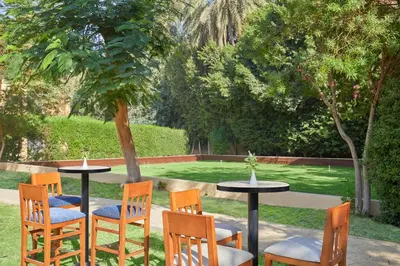 a group of chairs and tables in a garden at Steigenberger Resort Achti in Luxor