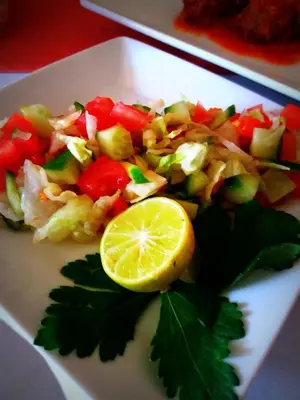 a white plate with a salad with a lemon on it at Elaria Hotel Hurgada in Hurghada