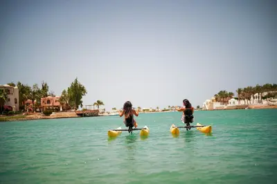 two girls are riding on kayaks in the water at Ali Pasha Hotel in Hurghada