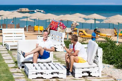 two men sitting on lawn chairs at the beach at Three Corners Sunny Beach Resort in Hurghada
