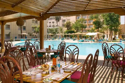 a restaurant with tables and chairs next to a pool at Aracan Eatabe Luxor Hotel in Luxor