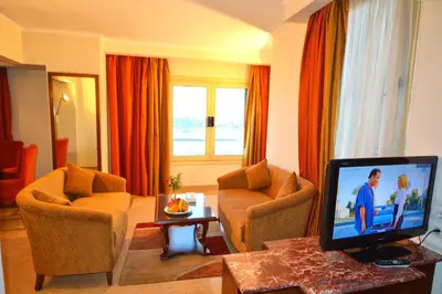 a living room with a tv and two chairs and a couch at Aracan Eatabe Luxor Hotel in Luxor