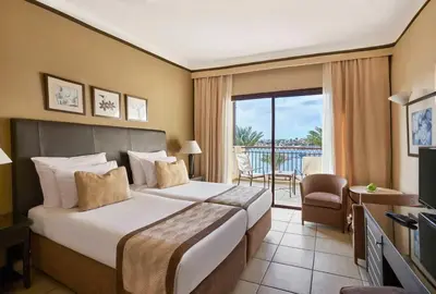 a hotel room with a bed and a balcony at JAZ Lamaya Resort in Coraya Bay