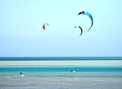 two people are flying kites in the ocean at Royal Beach Serviced Apartments in Hurghada