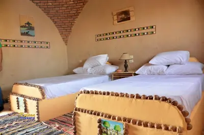 two beds in a room with two bedsitures at Qasr El Bagawat Hotel in ‘Ezbet Halfa