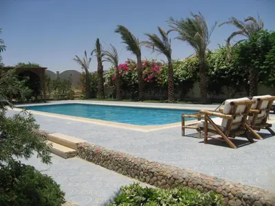 a swimming pool with two lounge chairs next to a resort at Villa Shahrazad Hurghada in Hurghada