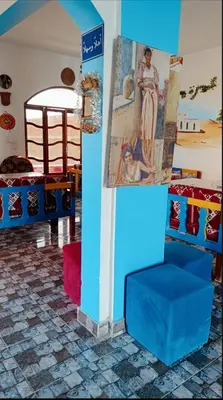 a room with a blue chair and a painting on a wall at Fadlos Anay Nubian Guesthouse فضلوس أناي in Aswan