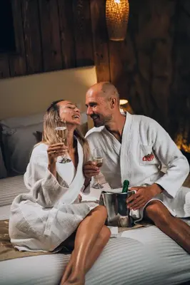 a man and woman sitting on a bed drinking wine at Caves Beach Resort Adults Only in Hurghada