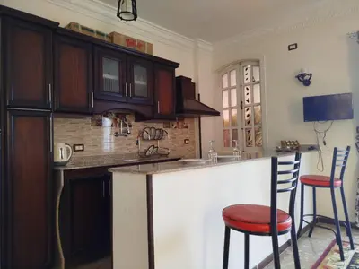 a kitchen with wooden cabinets and a counter with stools at Luxor Star Apartments in Luxor