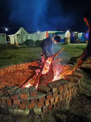 a man standing over a brick fire pit at night at Nuba Narty in Aswan