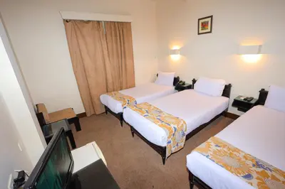 a hotel room with two beds and a flat screen tv at Hapi Hotel in Aswan