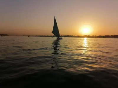 a sail boat in the water at sunset at Luxor palace Apartments in Luxor