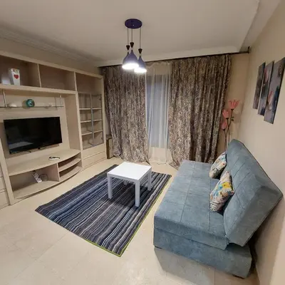 a living room with a blue couch and a tv at Esplanada Beach Apartment, no single men in Hurghada