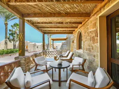 a patio with chairs and tables on a stone wall at Movenpick Resort El Quseir in Quseir