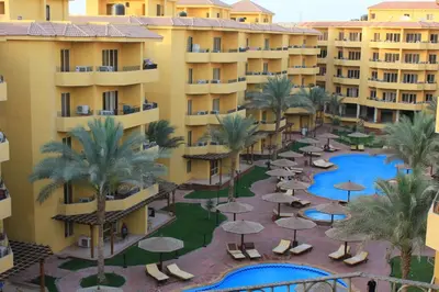 an aerial view of a resort with a pool and palm trees at Pool View Apartment at British Resort - Unit 02 in Hurghada