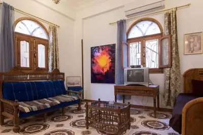 a living room with a blue couch and a tv at Terrasses et Jardins sur le Nil chez Hagag rive Ouest in Luxor