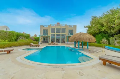 a swimming pool with benches and a building at Stunning Villa for Rent in El Gouna HEATED PRIVATE POOL in Hurghada