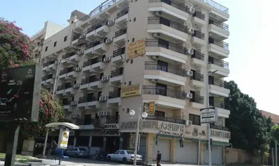 a tall white building with balconies on a city street at St.Joseph Hotel in Luxor